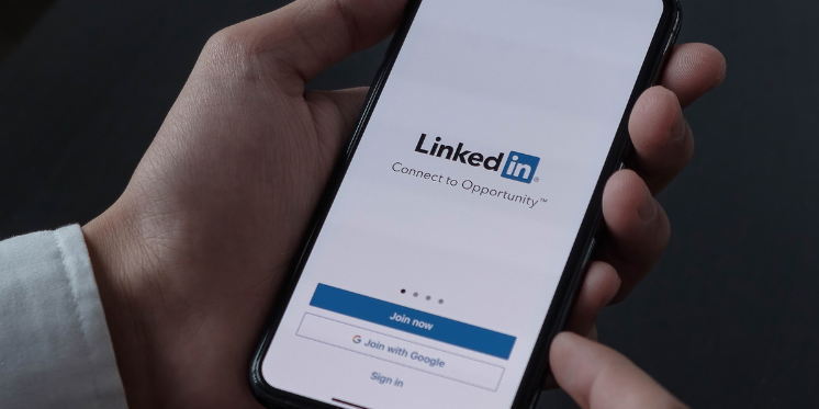 A man holding a phone with LinkedIn displayed. Create an engaging LinkedIn Profile